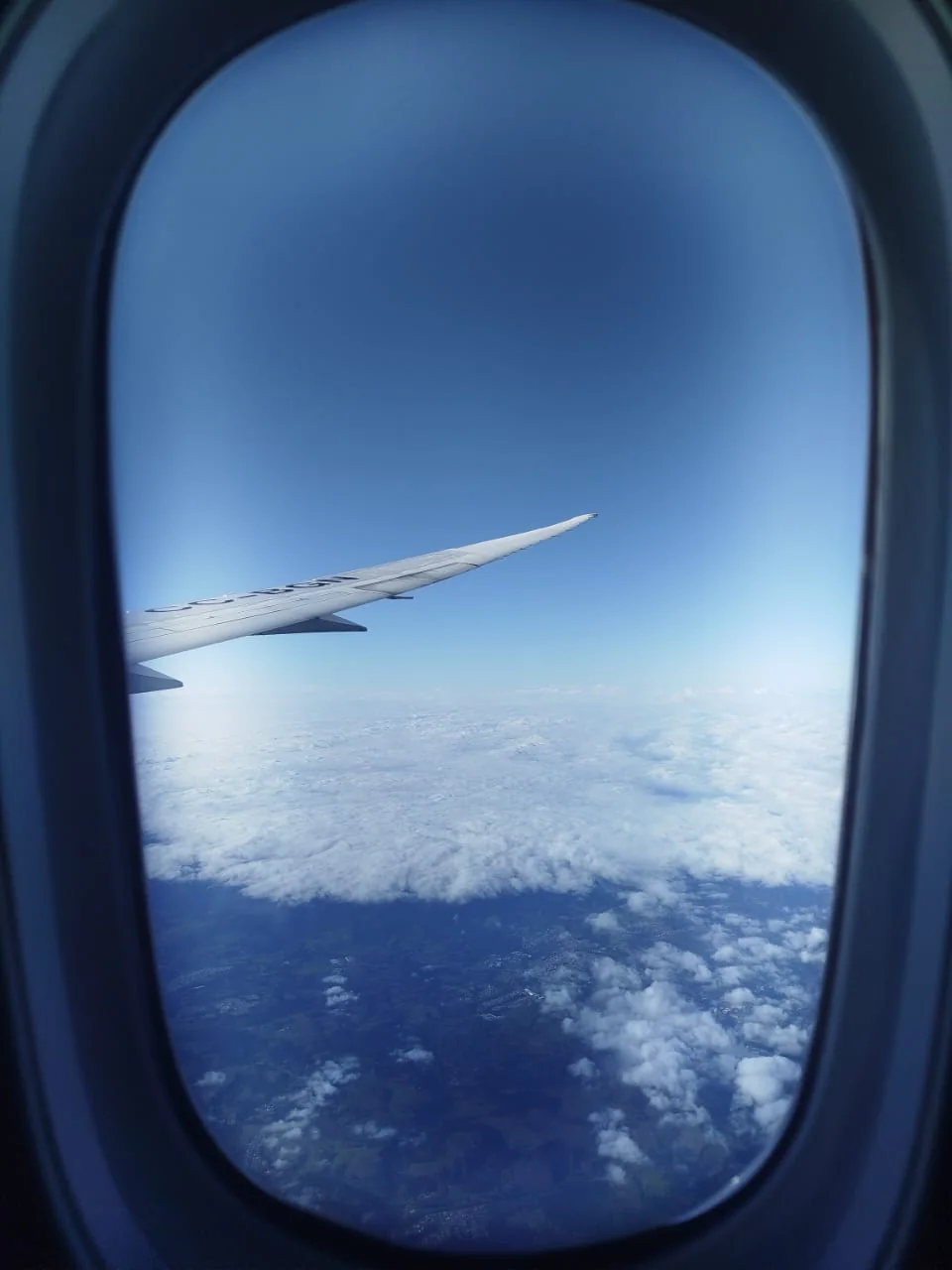 Vista do céu e das nuvens fotografada pela janela de um avião.
